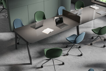 Top view of business interior with laptop and shared desk with chairs