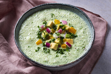 Green cucumber gazpacho cold cream soup styled and decorated in rustic bowl