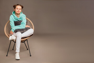 teenager sitting on a chair in a spacious empty studio on a gray background   