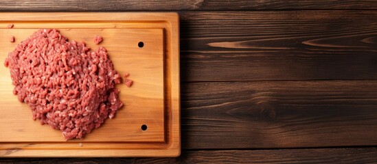 Top view of fresh, uncooked minced beef meat on a wooden butcher board with a cleaver. Wooden background.