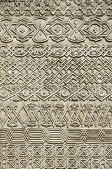 Carved embossed patterns on the  stone wall of an ancient church building as a background. Fragment, detail. Architectural features. Close-up. Selective focus.