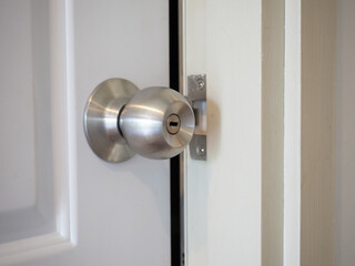 Stainless steel door knob or handle with keyhole on wooden door. Closeup photo, blurred.
