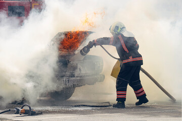Firefighters attack propane fire. Fireman Putting Out Fire. Firemen extinguishing a car fire.