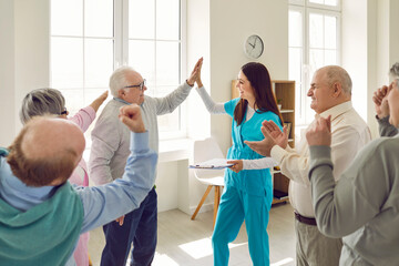 Friendly nurse, caregiver or psychologist woman giving high five to senior man during therapy in...