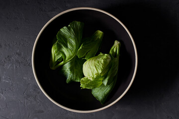 Tow view of a raw kale in a black bowl on gray background