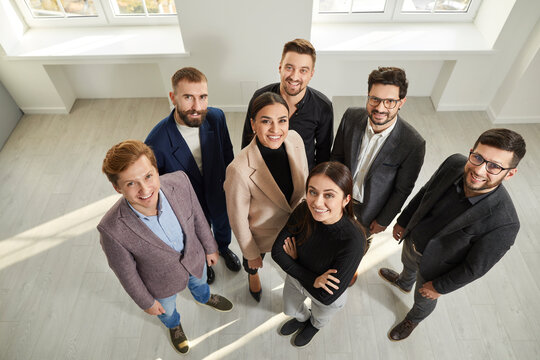 Top view of a group of business people men and women looking at the camera and smiling. Company employees team or a group of staff standing in the office confidently and cheerfully.