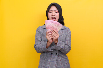 Shocked Asian muslim woman looking to the money in her hands. Business succesful and win money prize.