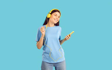 Girl with wired headphones connected to smartphone wearing in light blue shirt on same background. Concept of accessibility to music services wherever there is wireless internet.