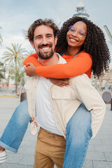 Verical portrait of couple embracing and having fun. Man giving his african american girlfriend a...