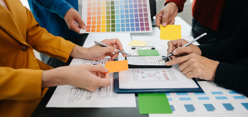  UX developer and ui designer brainstorming about mobile app interface wireframe design with customer breif and color code at office..