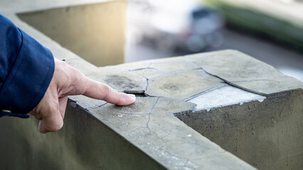 Male building inspector or construction worker hand pointing at grunge old crack wall. Building fracture and failure problem