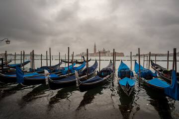 A wooden pier with a lantern and gondolas waiting for the tourists on a cloudy day in Venice Italy