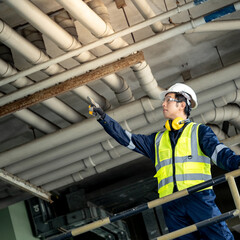 Asian male building inspection engineer pointing at plumber piping system. Construction worker man...