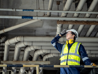 Asian man inspection engineer holding his safety helmet while looking at plumber piping system....