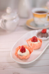 Close up of Japanese dessert chocolate and strawberry mochi or glutinous rice ball with strawberry topped. served on white plate and cup of tea. blurred background