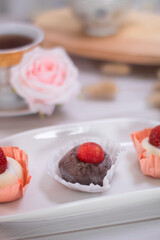 Close up of Japanese dessert chocolate and strawberry mochi or glutinous rice ball with strawberry topped. served on white plate and cup of tea. blurred background