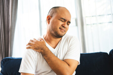 Man has problem with structural posture Neck and shoulder pain. Massaged his neck and shoulders for relief. reduce muscle tension on sofa couch in living room