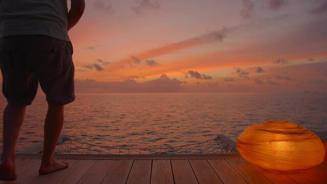 Man on mobile phone sitting watching sunset in tropical location