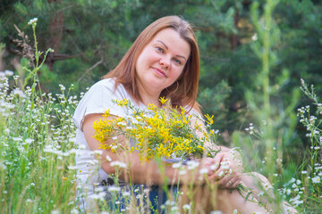 Close-up of a happy woman in the park sitting in flowers on a sunny day.