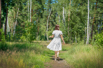 In the summer in the forest, a woman walks through the forest.