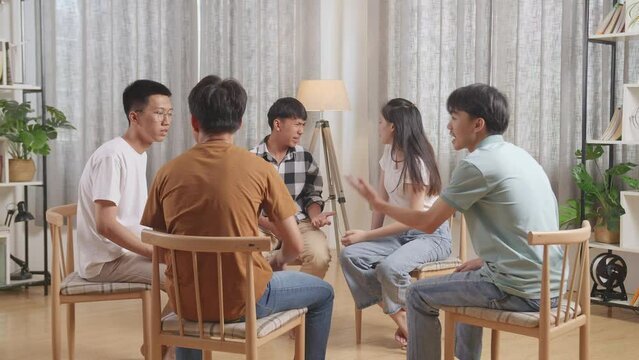 Asian Teen Group Sitting In Chairs Forming A Circle Arguing And Trying To Blame Each Other 

