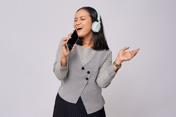 Beautiful young singer Asian woman 20s wearing formal grey shirt listening to music in headphones...