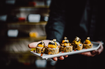 Man chef hand holding a plate full of sushi roll