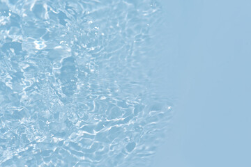 Blue water with ripples on the surface. Defocus blurred transparent blue colored clear calm water surface texture with splashes and bubbles. Water waves with shining pattern texture background.
