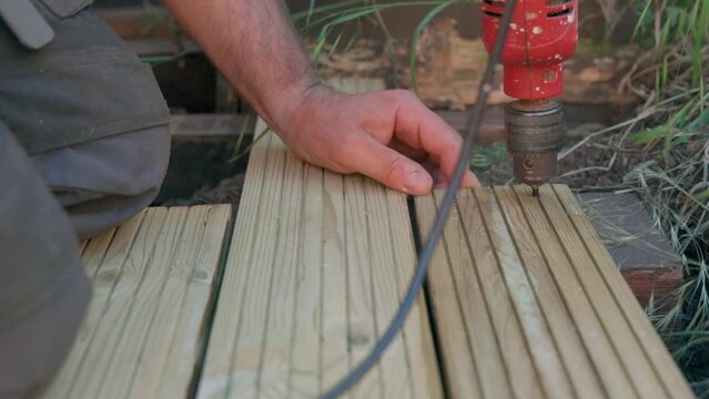 Male builder using drill to screw the screws off the timber
