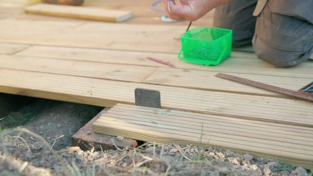 Male builder using drill to screw the screws off the timber