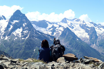Dombay, Karachay-Cherkess Republic, July 2023, two tourists admire the mountains, sitting on a...