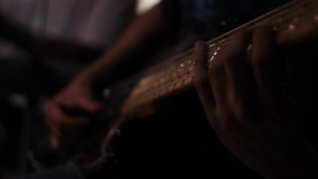 detail of hands playing guitar at night show