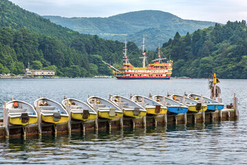 Pleasure boats on Lake Ashi, also know as Hakone Ashinoko Lake, a crater lake in an extinct volcano in Hakone, Japan. - obrazy, fototapety, plakaty