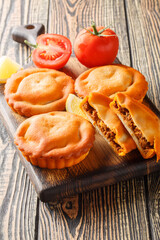 French closed pie tielle with seafood and vegetables close-up on a wooden board on the table. Vertical