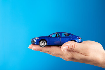 Buying a car, Motor vehicle rent, Lease or purchase, car in hand on a blue background, copy space