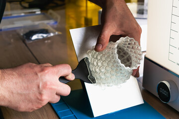 Man holding a 3d resin object with next to him wash and cure machines