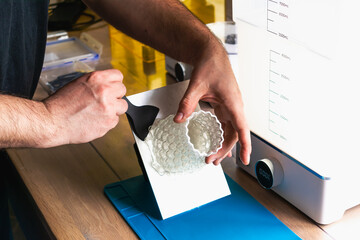 Man holding a 3d resin object with next to him wash and cure machines