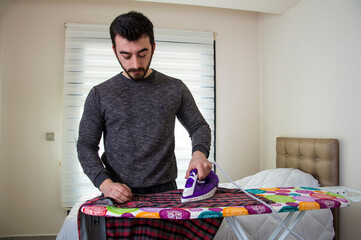 man irons shirt on ironing board