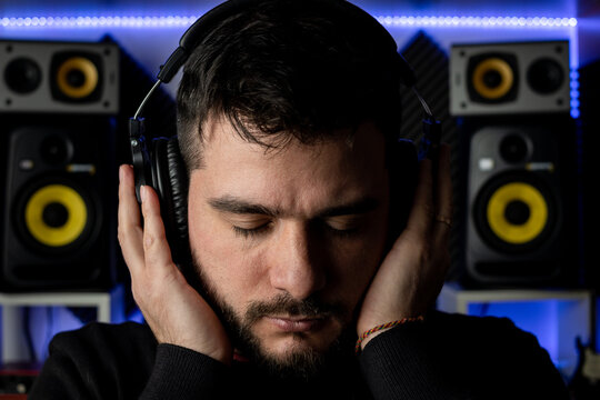 Productor musical trabajando en su estudio, escuchando atentamente sus auriculares