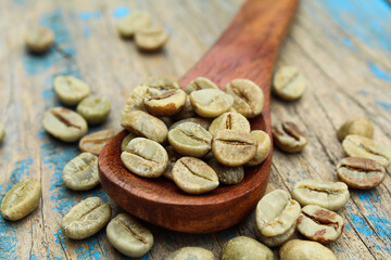Green coffee beans in a wooden spoon close-up view 