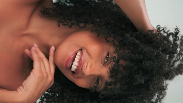 Vertical portrait of young smiling model with curly hair in afro style and bright makeup