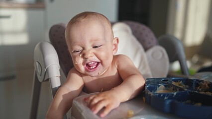 baby dirty eats. happy family a child toddler concept. baby dirty sitting messing with food at the...