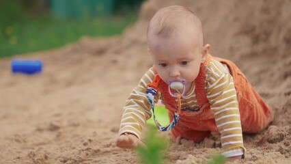 baby baby close-up in colorful sandbox. happy family kid dream concept. boy is playing on the playground. kid is sitting in sand playing with his toys. small child climbs on the yellow sand lifestyle