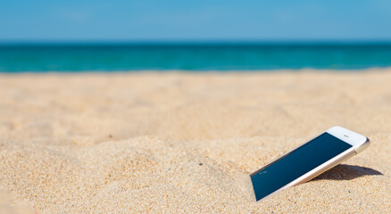 cell phone buried in the sand of a majestic summer day beach in high resolution