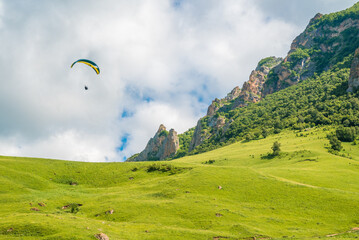 A paraglider flies by parachute over the mountains