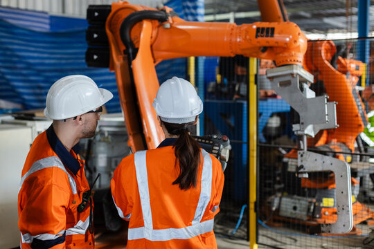 Mechanic engineer man and woman using talkie walkie are checking quality system of machines before use. Service programming machinery at factory industry.