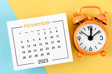 The November 2023 Monthly calendar for 2023 year with alarm clock on beautiful background.