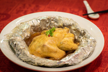 traditional asian double boiled herbal whole chicken meat soup wrap in aluminium foil on red table chinese new year cuisine halal food restaurant banquet menu