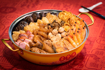 traditional asian luxury treasure premium seafood Peng cai abalone, sea cucumber, scallop, prawn, oyster, mushroom in hot clay pot on red table for Chinese new year cuisine halal banquet food menu