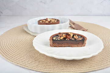 freshly handmade beautiful France rocher dark chocolate layer tart w mixed macadamia peanuts on white marble luxury background with bamboo decoration halal food dessert menu for cafe